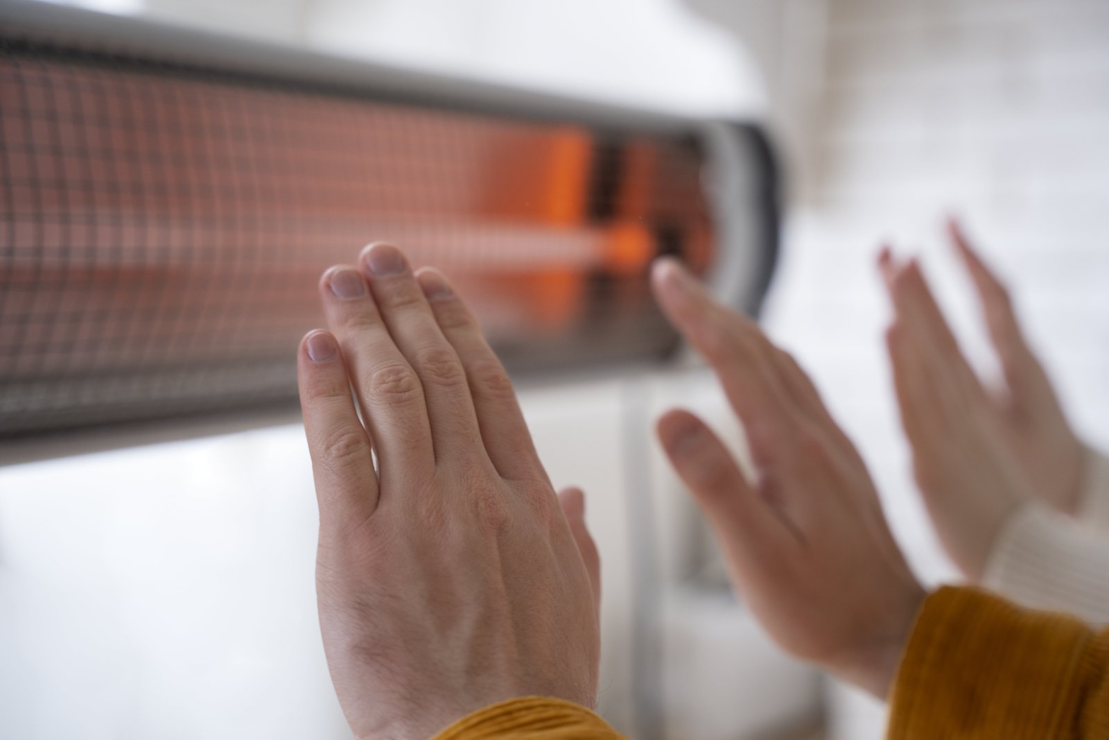 close-up-people-warming-up-hands-near-heater (1)-min