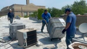 Modern HVAC Tech crew bringing in a new unit next to the old system for air conditioner replacement in Lincolnwood